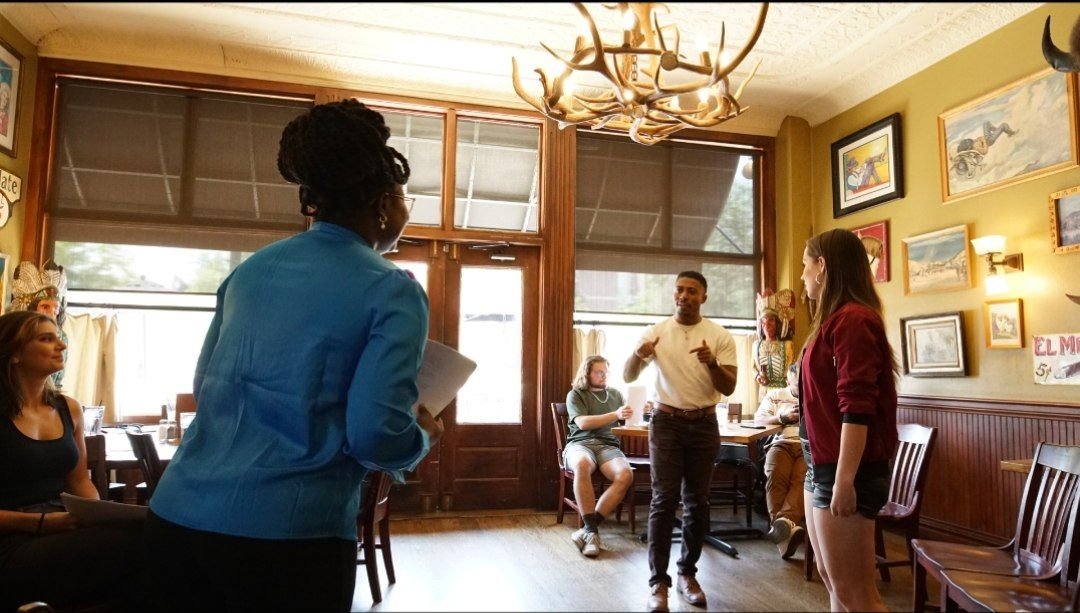 Reine directing cast members in the coffee shop during Between Two Lives