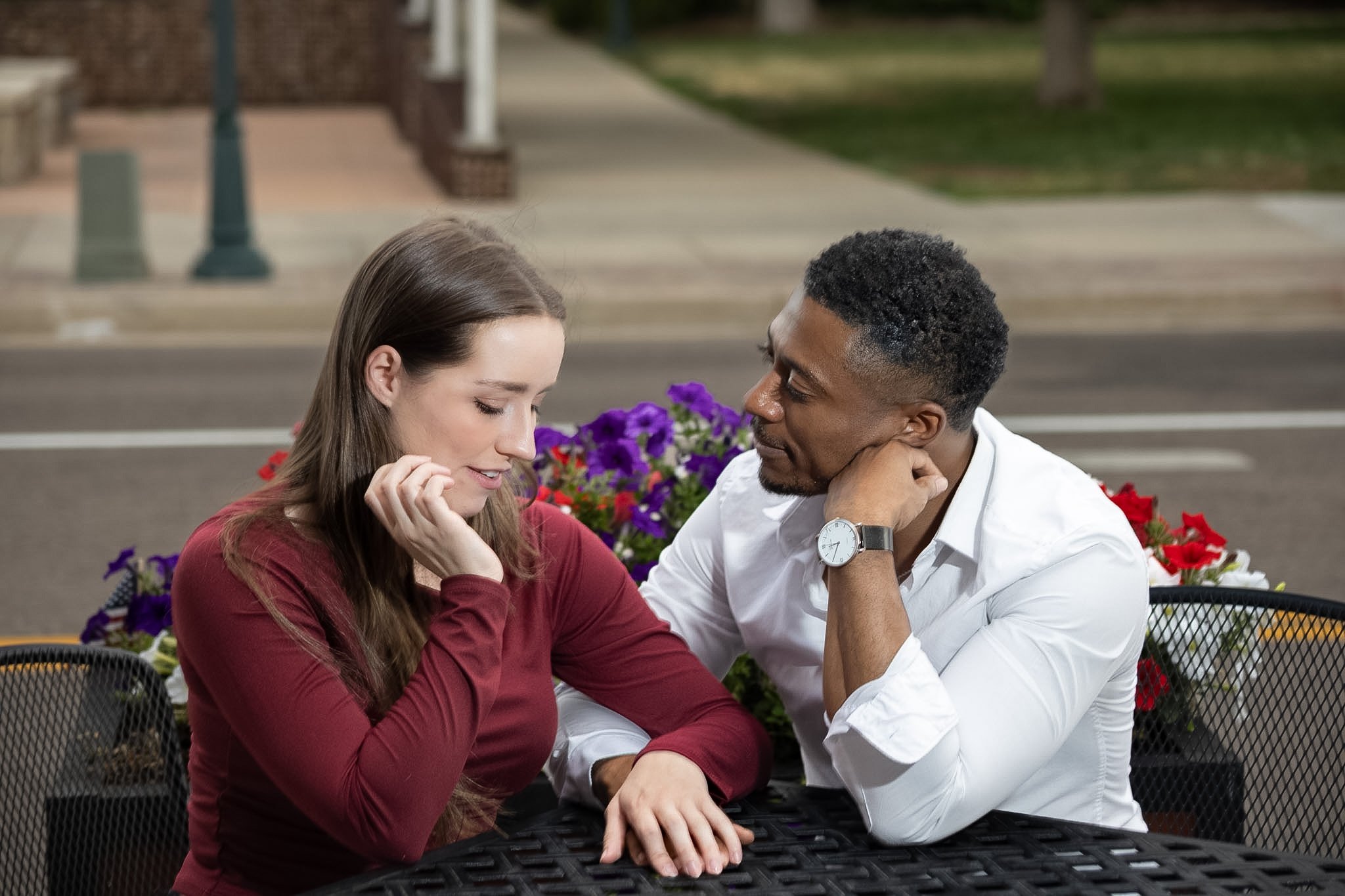 Between Two Lives couple seated at an outdoor café table among flowers