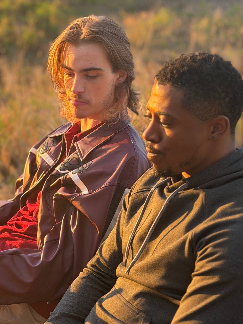 Two men sitting on a park bench in golden light in Between Two Lives